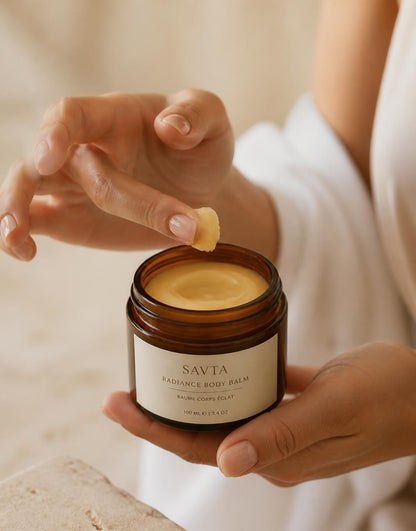 Hands scooping golden tallow honey balm from an amber glass jar